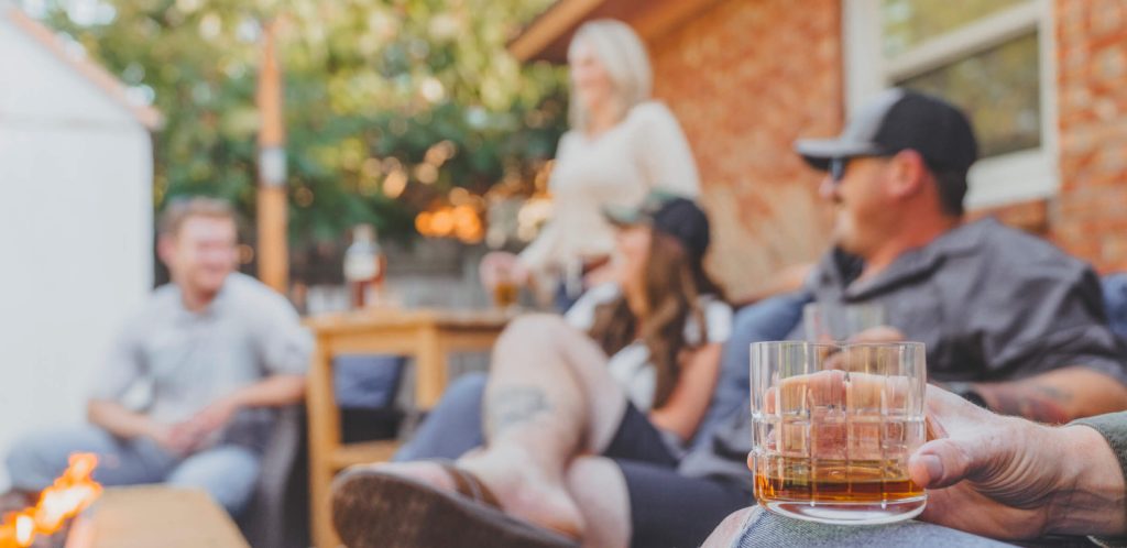 Friends enjoying whisky while grilling