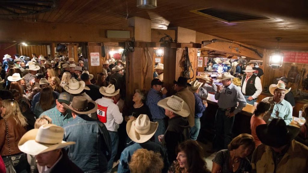 Crowd in cowboy hats filling the wood-paneled Let ’Er Buck Room bar at the Pendleton Round-Up